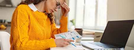 woman in orange sweater stressed reviewing financial documents